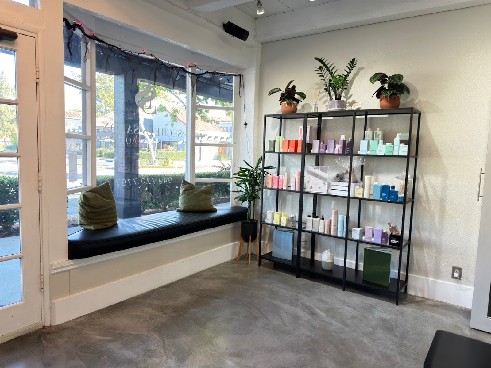 The window seat at Secrets Salon with green pillows and a product shelf