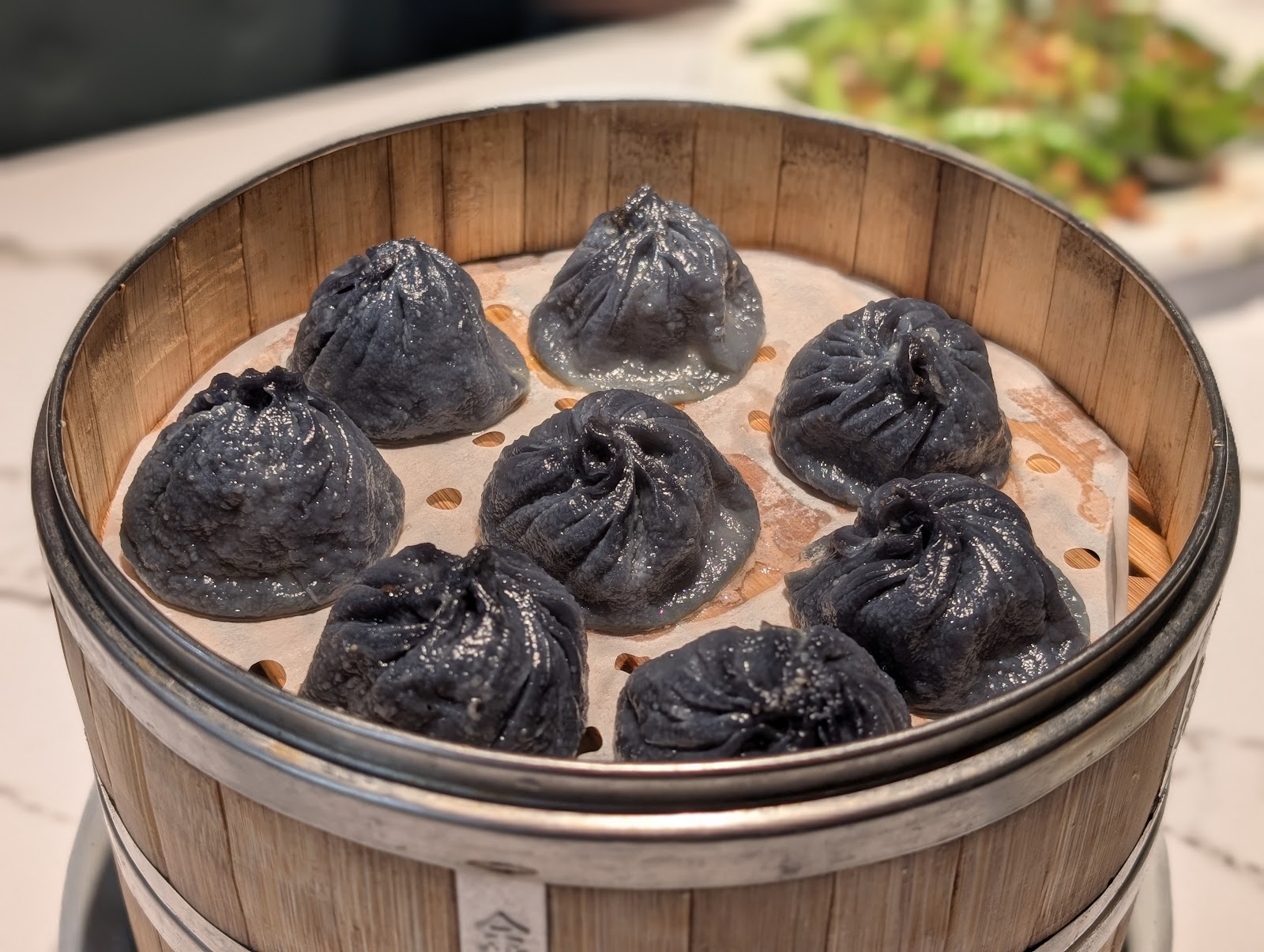 Black squid-ink soup dumplings arranged in a bamboo steamer