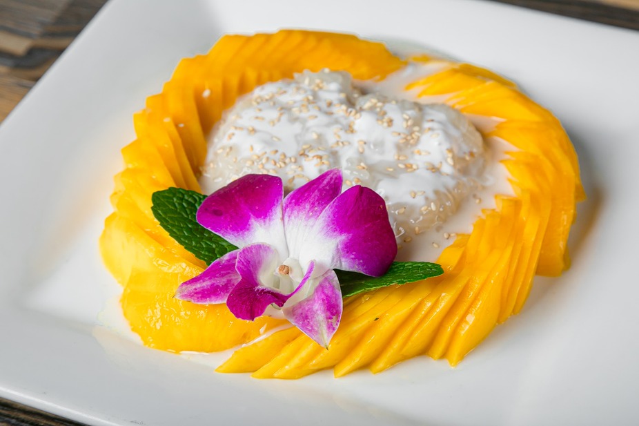 Mango sticky rice at SIAM, fanned ripe mango around coconut sticky rice topped with toasted sesame, mint, and a purple orchid