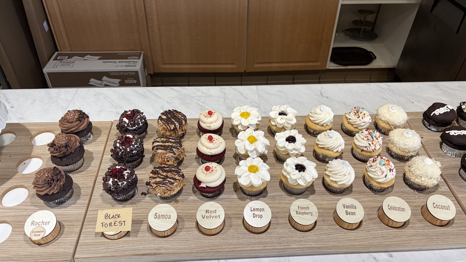 The Simply Cakes cupcake case with hand-lettered wooden flavor labels
