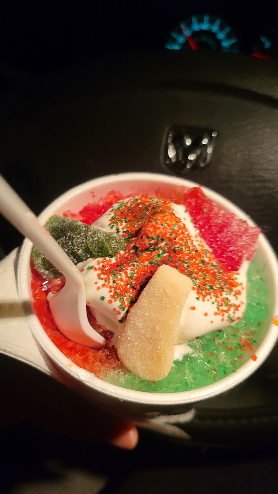 A rainbow shave ice with gummy candies, sprinkles, and a swirl of whip at Sno 2 Go