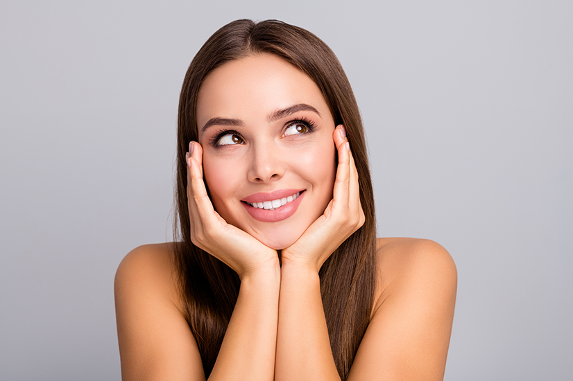 A close, calm portrait of a smiling woman with smooth, radiant skin