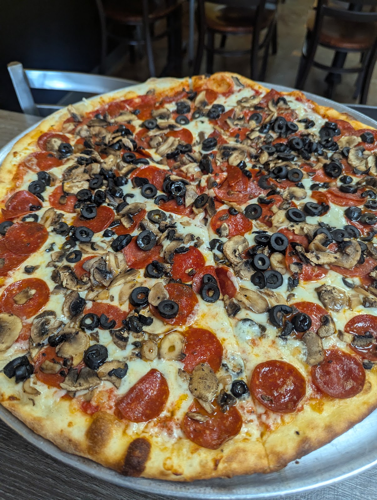A whole pepperoni-mushroom-olive pizza at Terra Mia, the table favorite, served on a silver pan