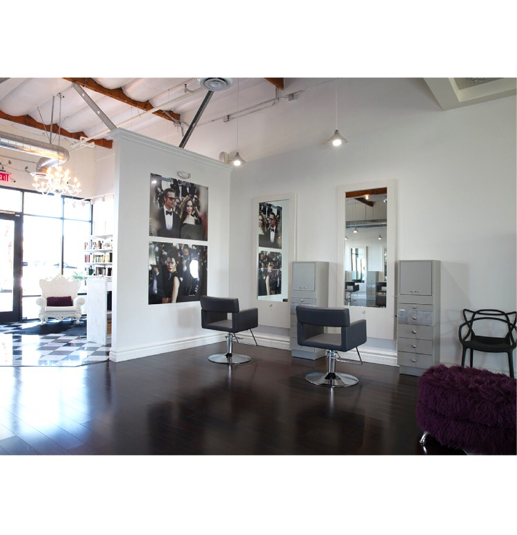 The entry of the house salon: white walls, dark walnut floor, a chandelier, a baroque white chair and checkerboard tile by the front windows