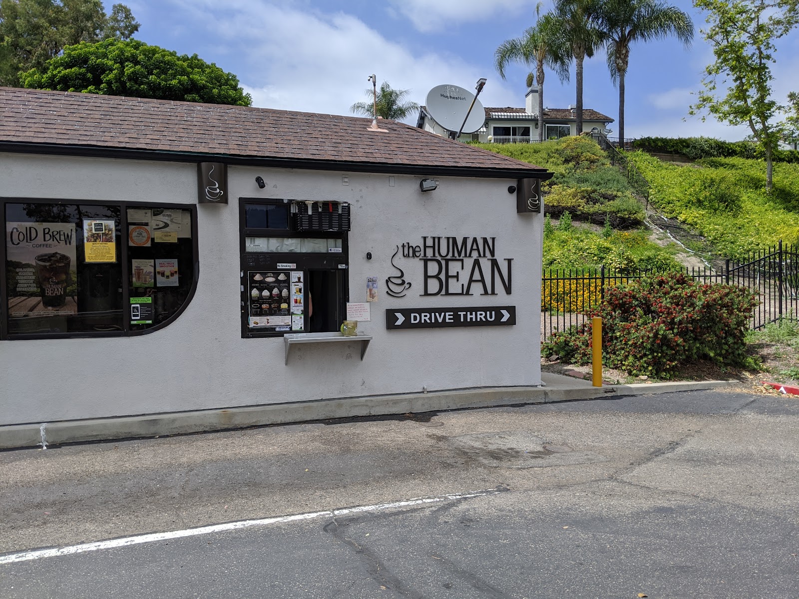 The Human Bean drive-thru shack on El Toro Road in Lake Forest, white stucco with a brown shingle roof and the steaming-cup logo over a DRIVE THRU sign