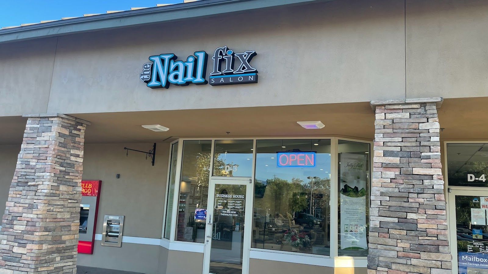 The Nail Fix storefront in Ladera Ranch: a stone-column suite with the teal sign and a blue OPEN light