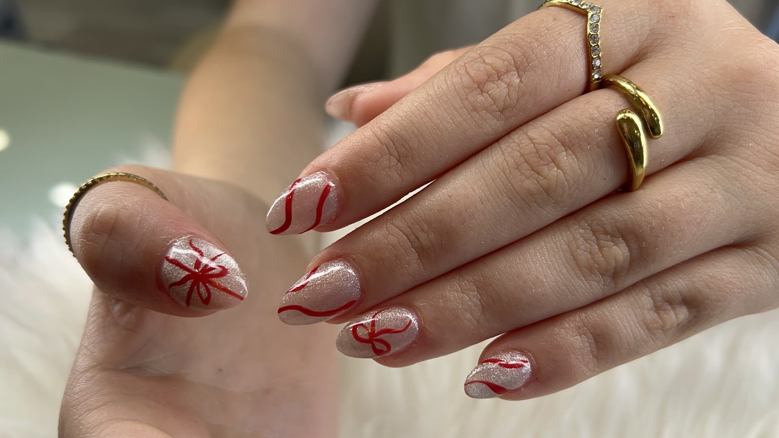 Shimmer almond nails with hand-painted red ribbon line art
