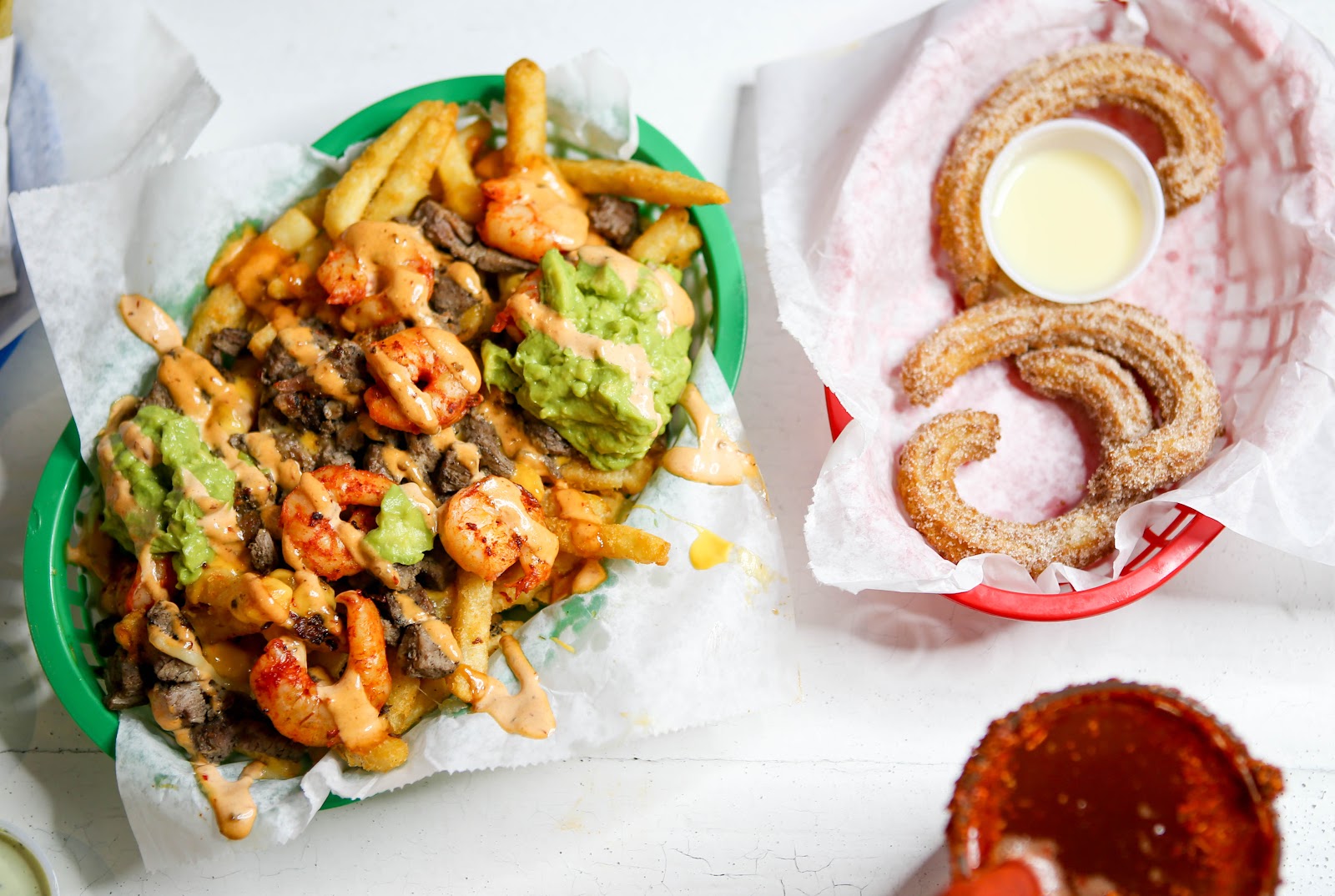 Mar y tierra loaded fries beside cinnamon-sugar churros and a cup of salsa at The Taco Stand