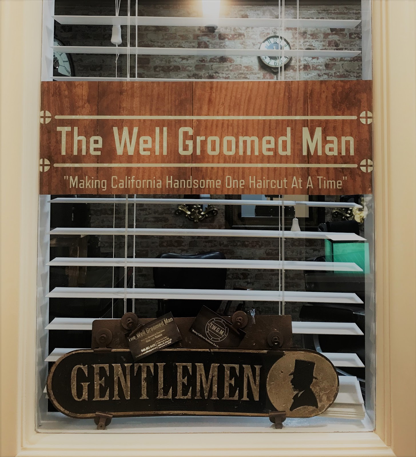 Storefront sign reading The Well Groomed Man, Making California Handsome One Haircut At A Time, with a GENTLEMEN placard