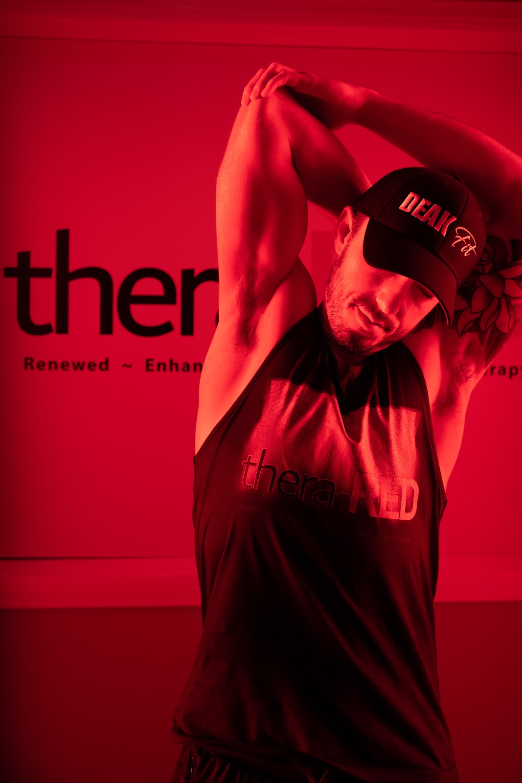 A guest in the Thera-RED studio in front of the brand wall and the red light panel