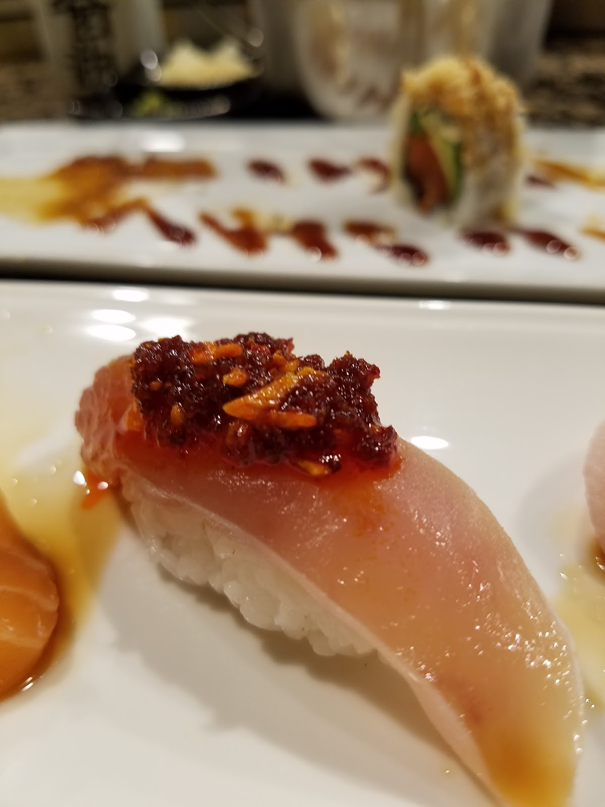 Seared hamachi yellowtail nigiri topped with a chili-garlic relish, photographed close at the Totoya sushi bar