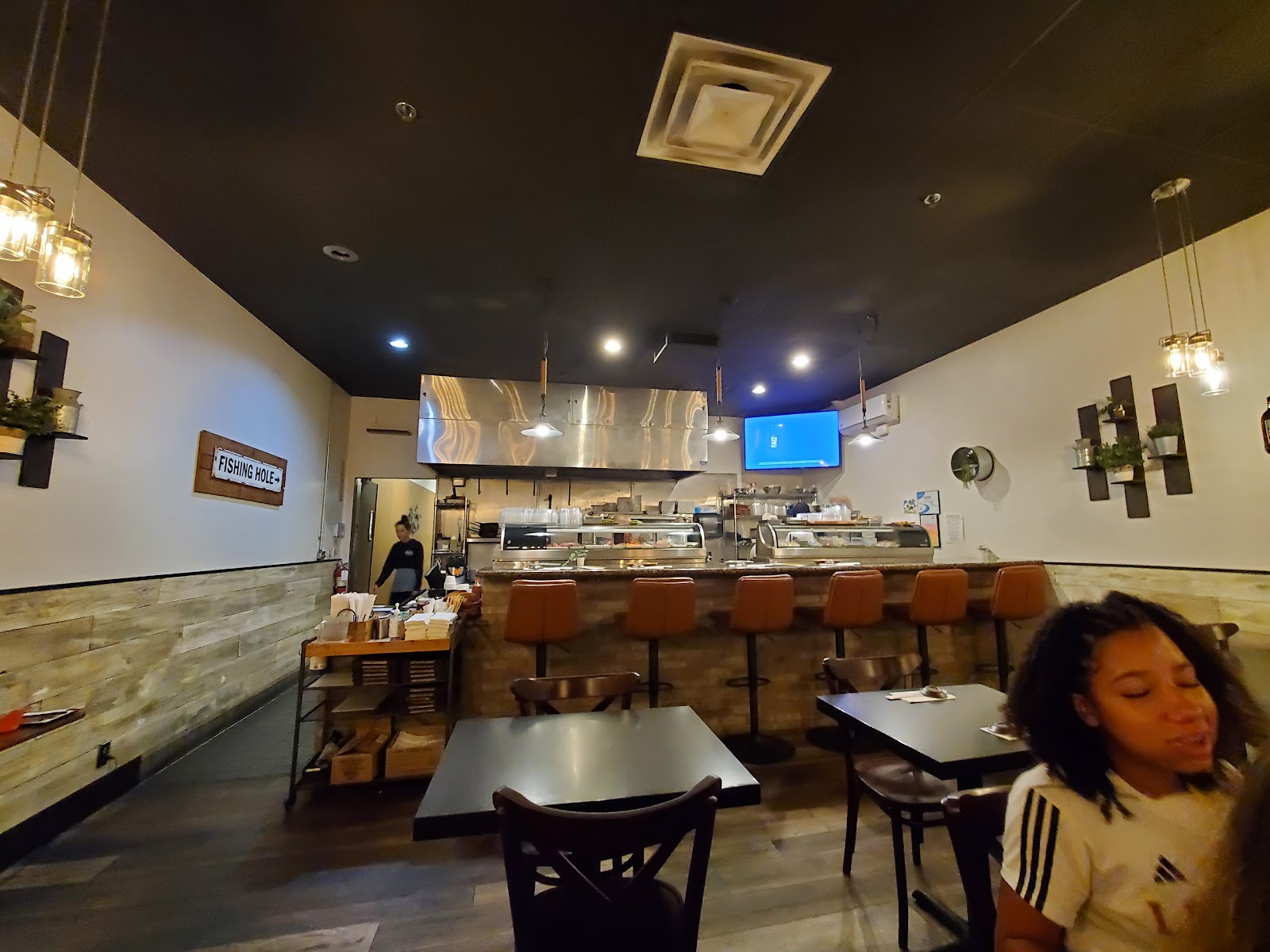 Inside Totoya, the sushi bar with leather stools and warm wood under the FISHING HOLE sign