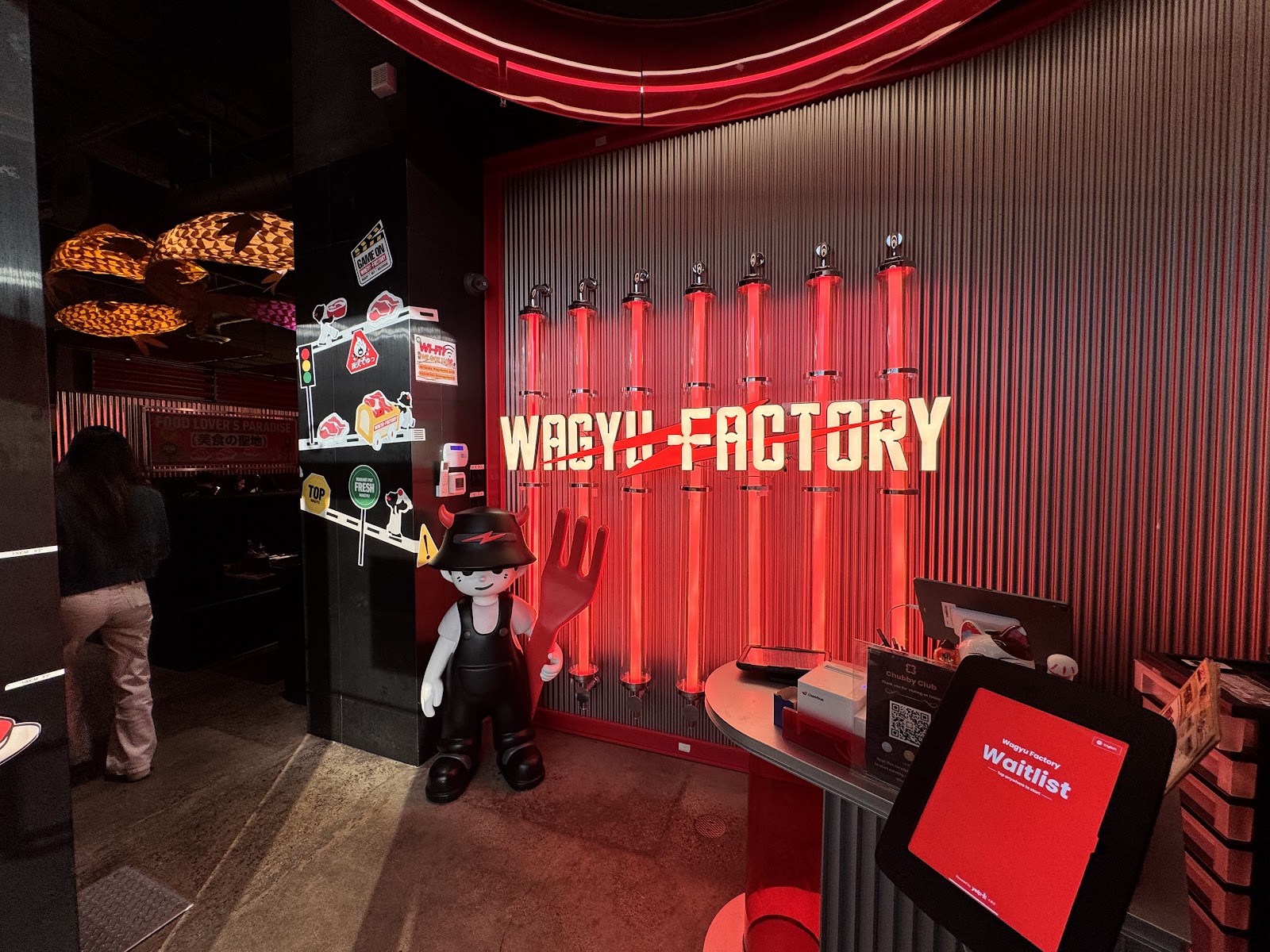 The Wagyu Factory storefront wall with the gold WAGYU FACTORY wordmark struck through with a red line and red neon tubes
