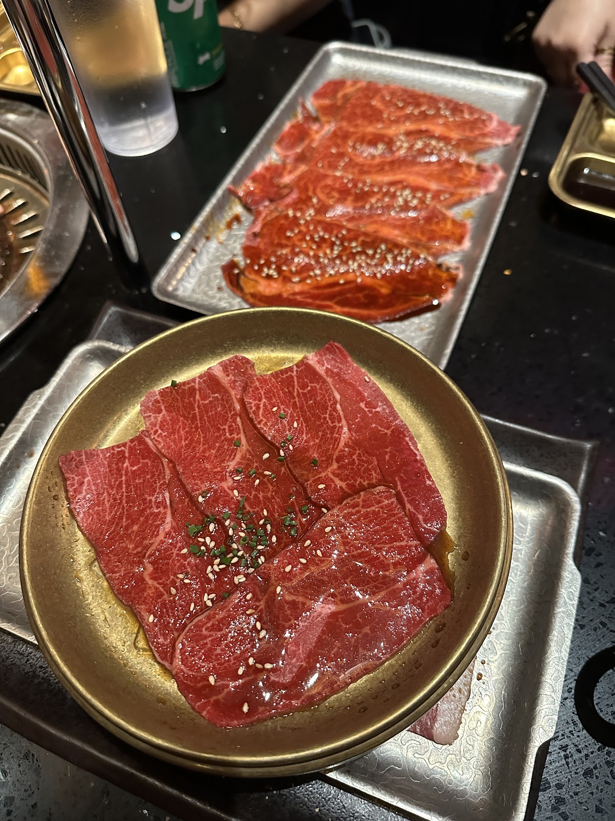Marbled wagyu beef fanned on a gold plate beside a metal tray of sauced short rib at Wagyu Factory