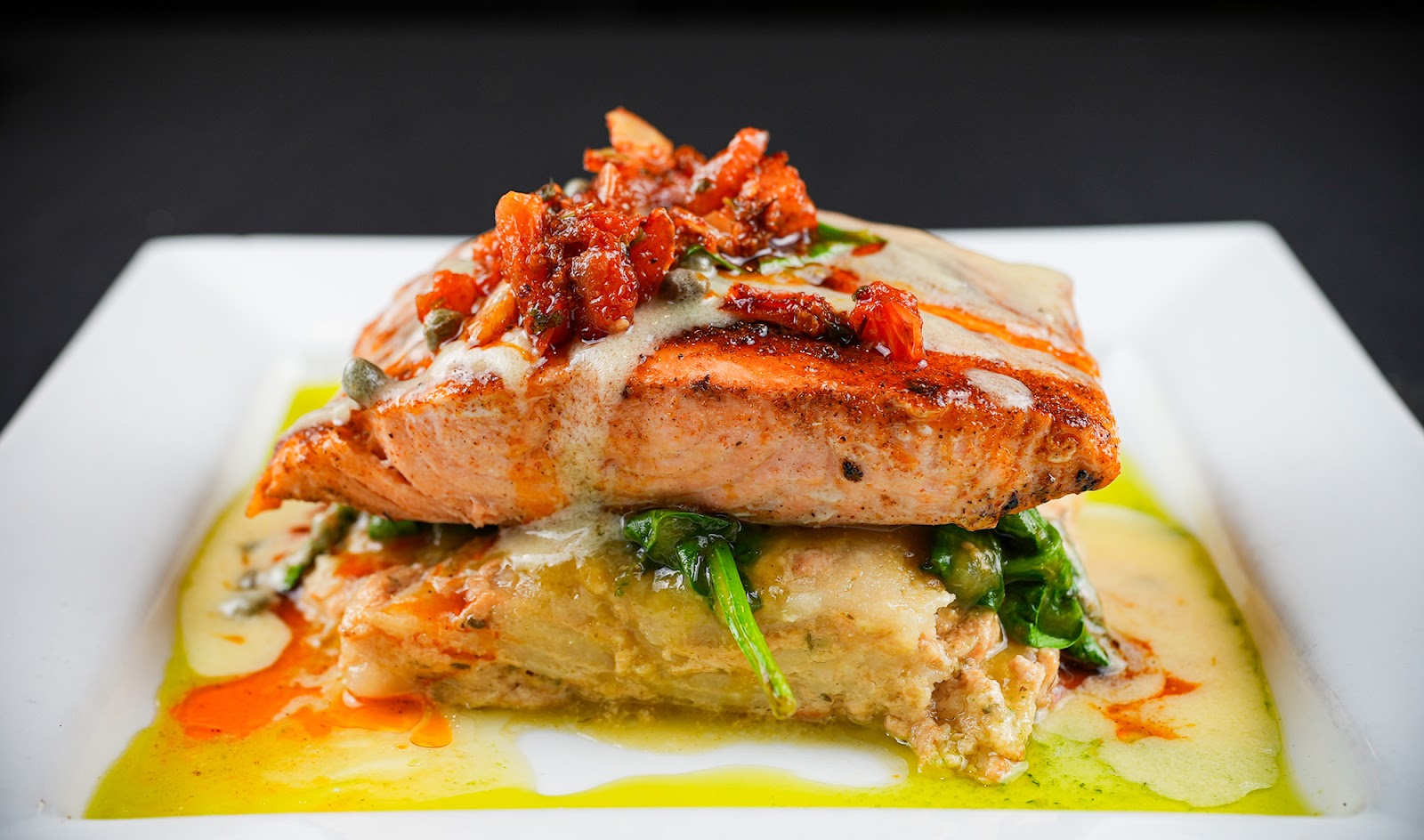 A plated upscale Mexican entree at Xclusive, glossy sauce and bright garnish on a white plate against a dark backdrop