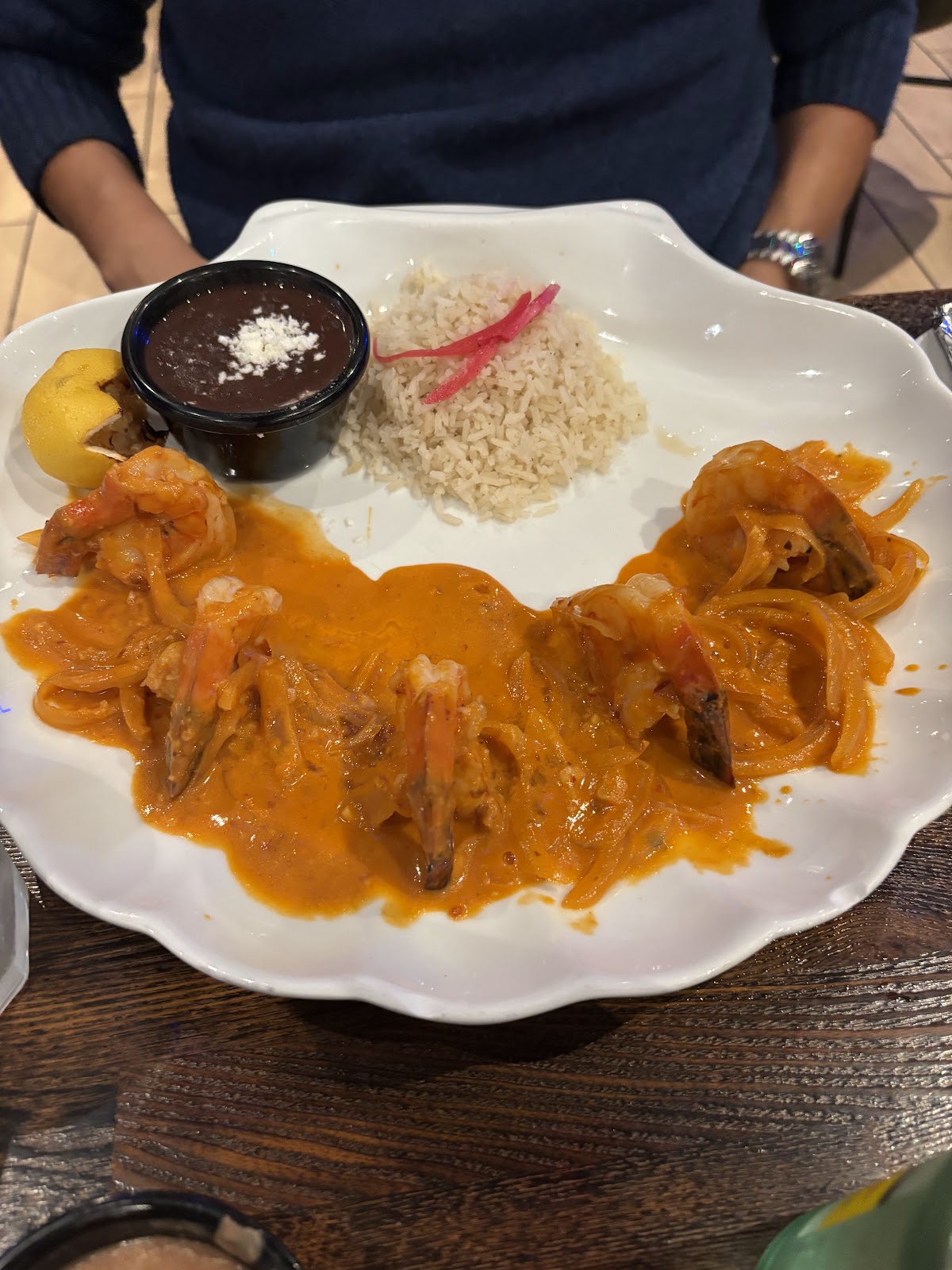 Shrimp a la diabla in red sauce with rice and black beans on a scalloped plate at Xclusive Mexican Kitchen