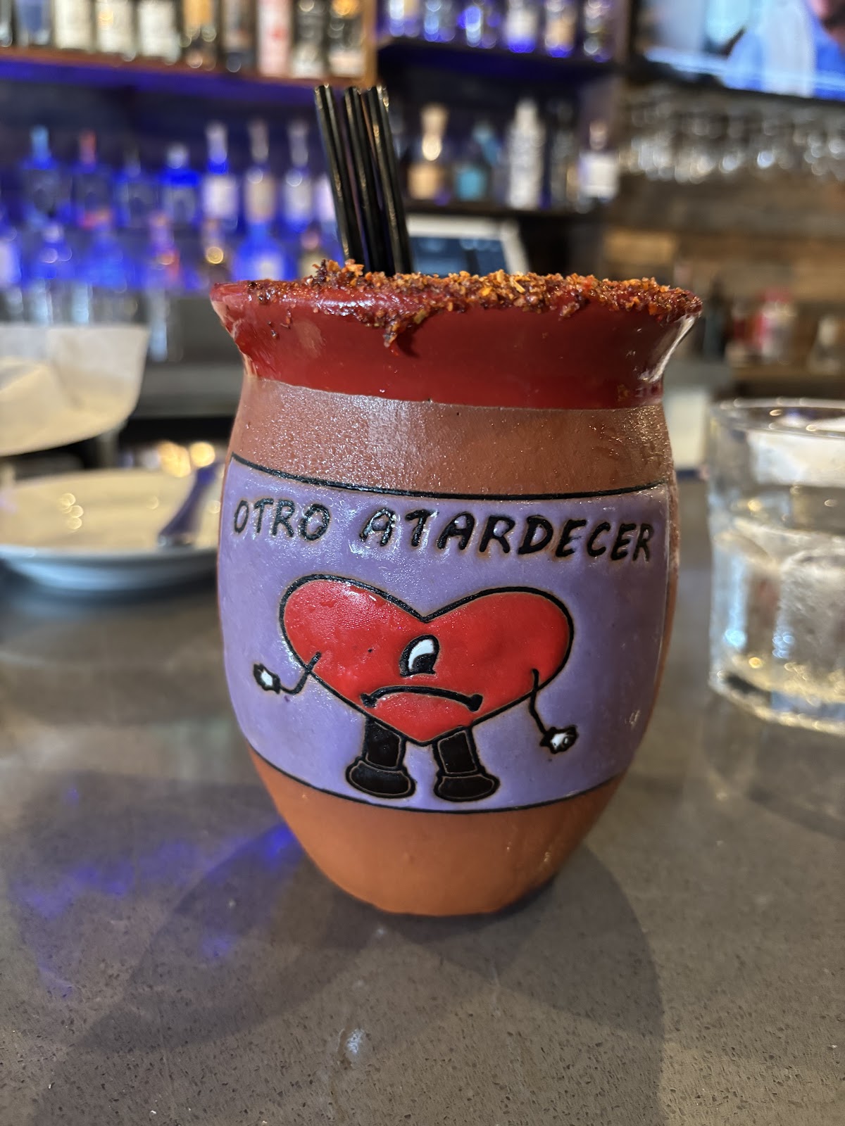 A house cocktail at Xclusive Mexican Kitchen served in a hand-painted clay cup with a chamoy and tajín rim